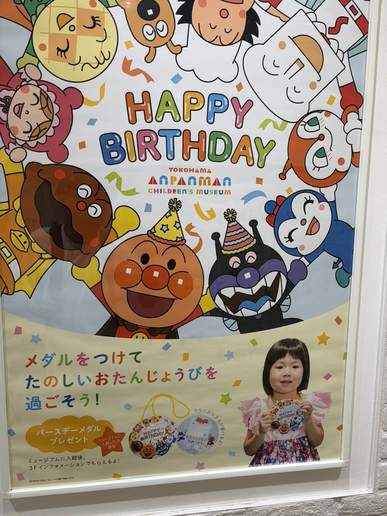 アンパンマンミュージアム横浜誕生日特典の紹介ポスターの写真
真ん中にHAPPYBITHDAYと文字がありその周りにアンパンマンやばいきんまんなどが輪を作っている